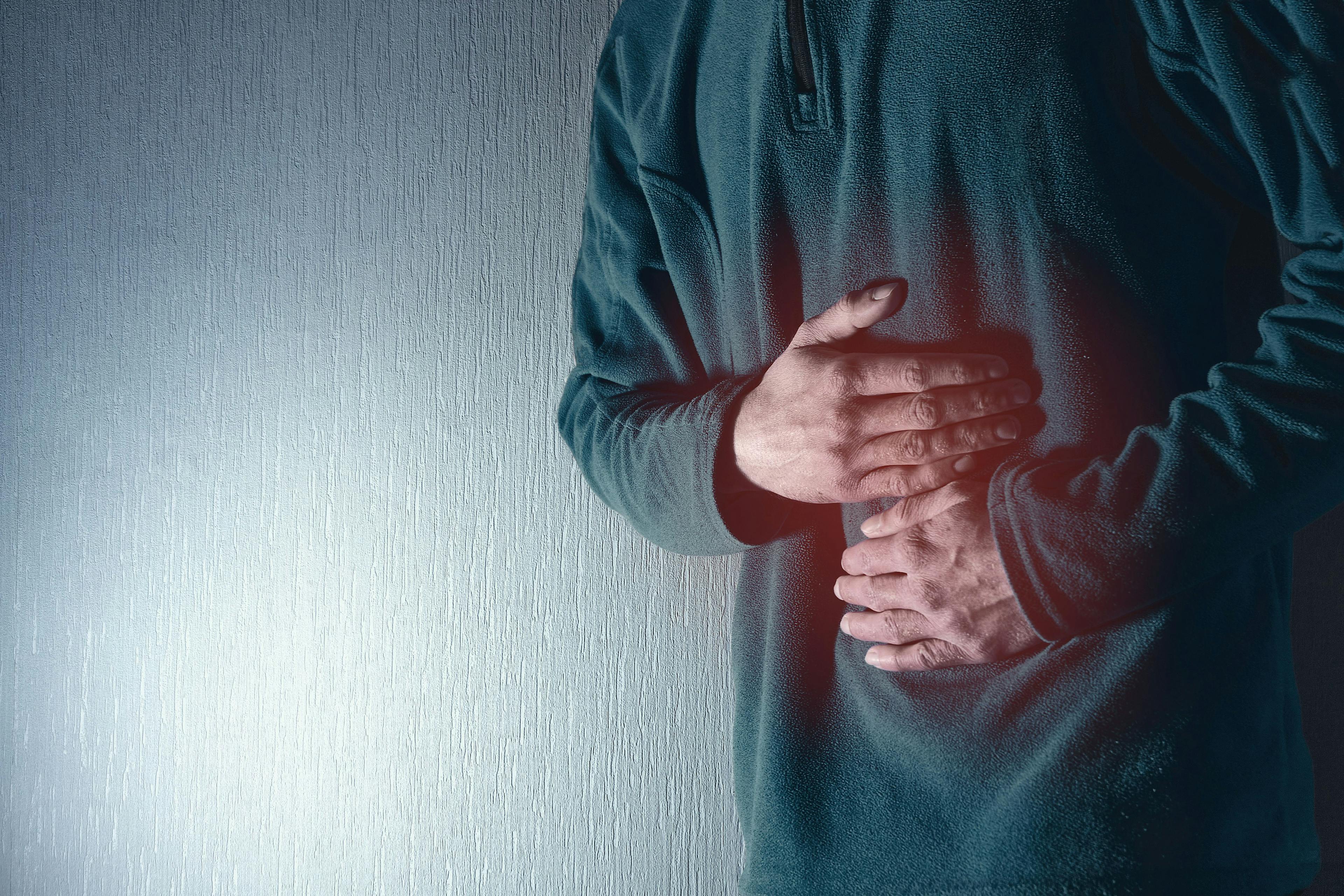 Man holds his belly with both hands. Stomach ache. Gastritis. Blue grey background - Image credit: Fotografie-Schmidt | stock.adobe.com