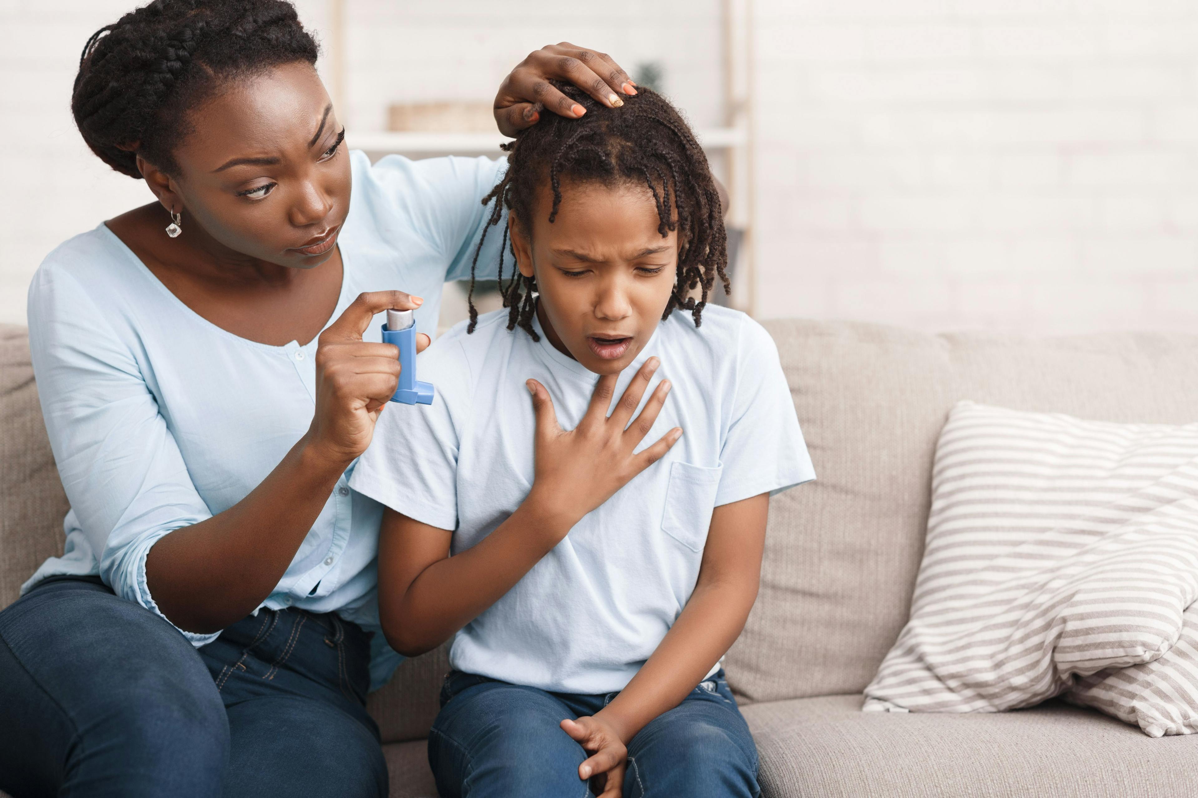 mother holding asthma inhaler for child coughing