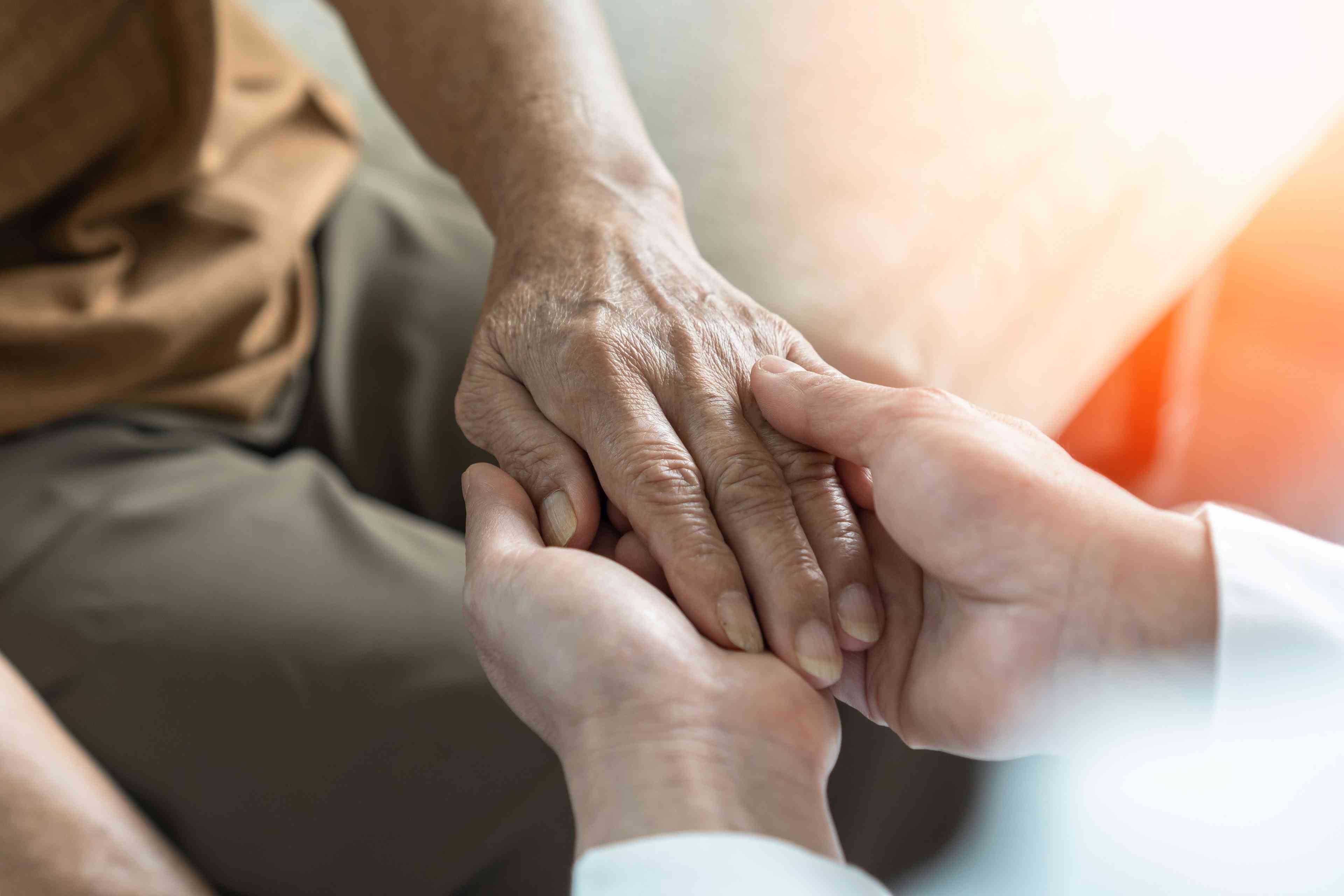 Caregiver holding elderly man's hand -- Image credit: Chinnapong | stock.adobe.com