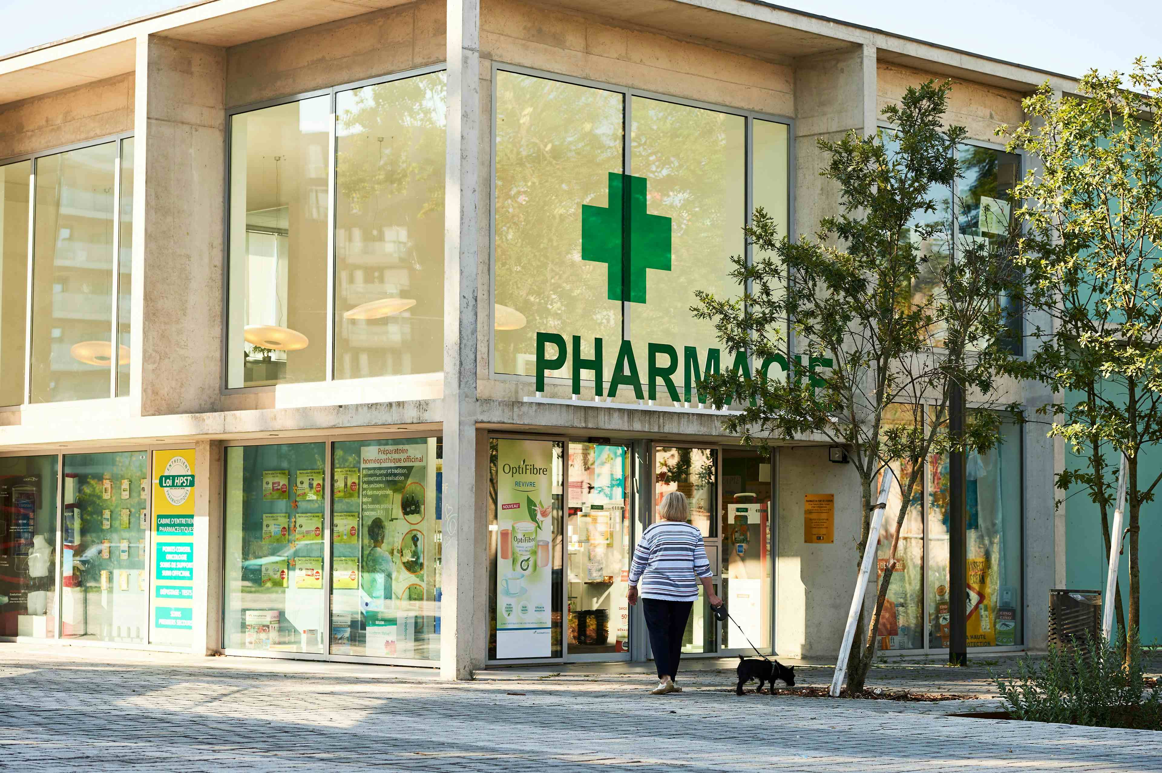 Adult woman with dog walking toward pharmacie