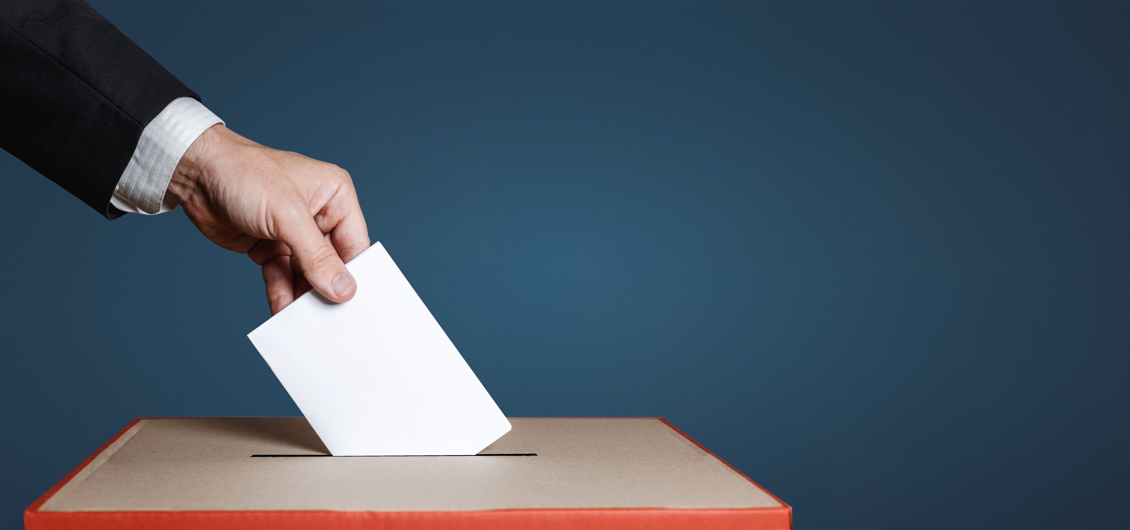 Voter Holds Envelope In Hand Above Vote Ballot On Blue Background. Freedom Democracy Concept - Image credit: tinyakov | stock.adobe.com 