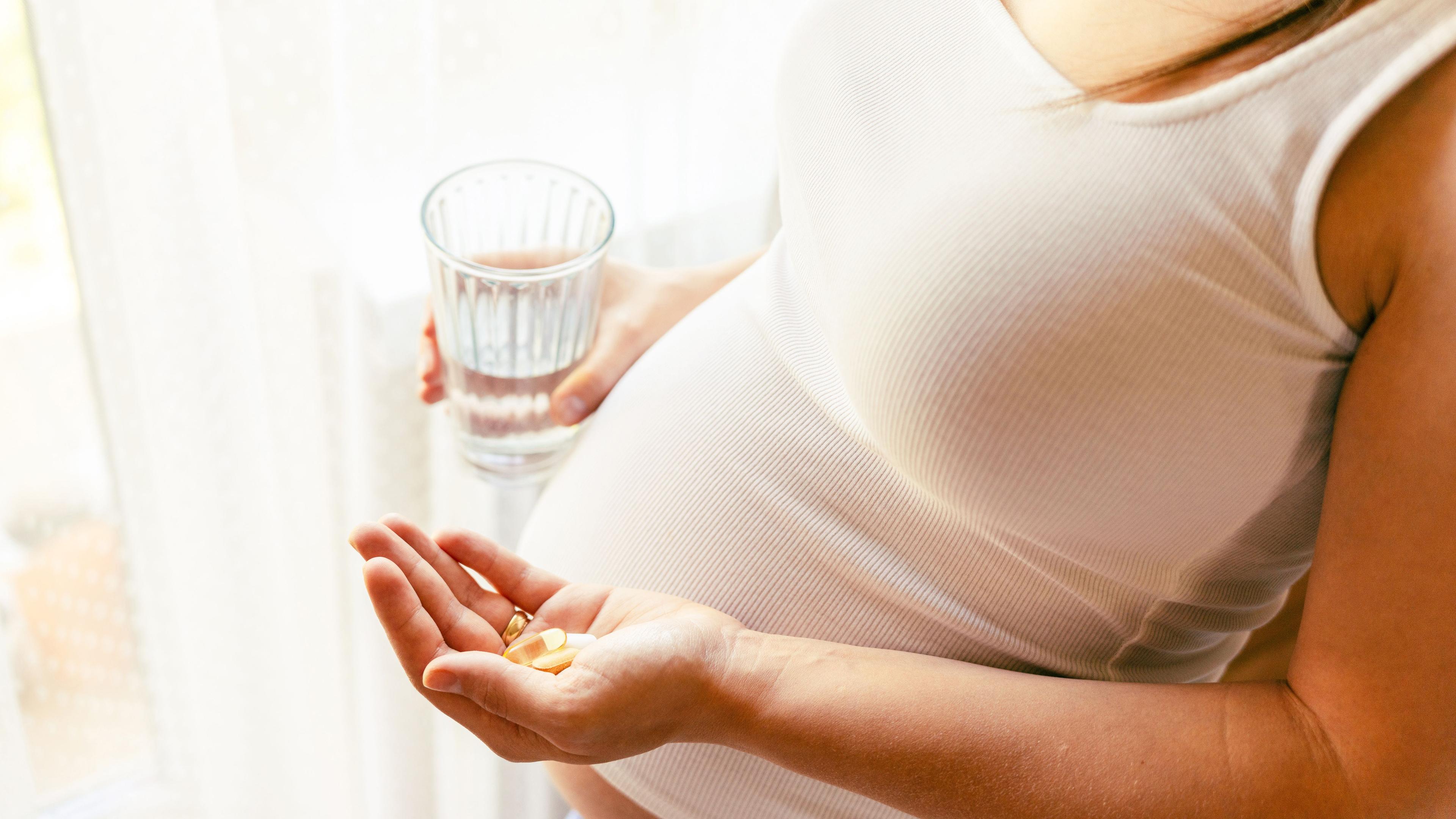 Supplements vitamins pill. Happy young pregnant woman holding supplement vitamin pill. Therapy, healthcare, motherhood concept - Image credit: Maksym | stock.adobe.com 