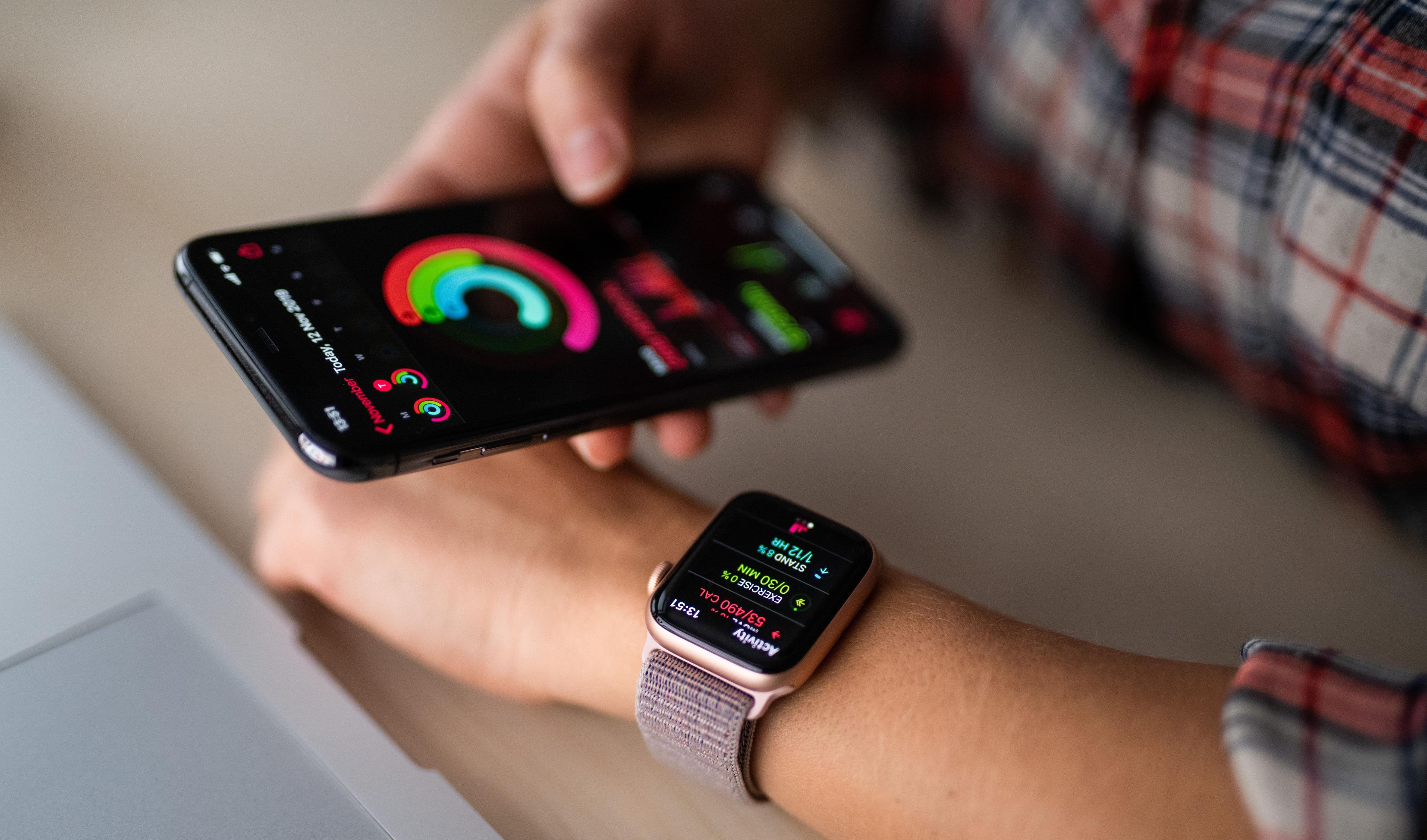 Woman wearing a smart watch and looking at a smartphone with health data