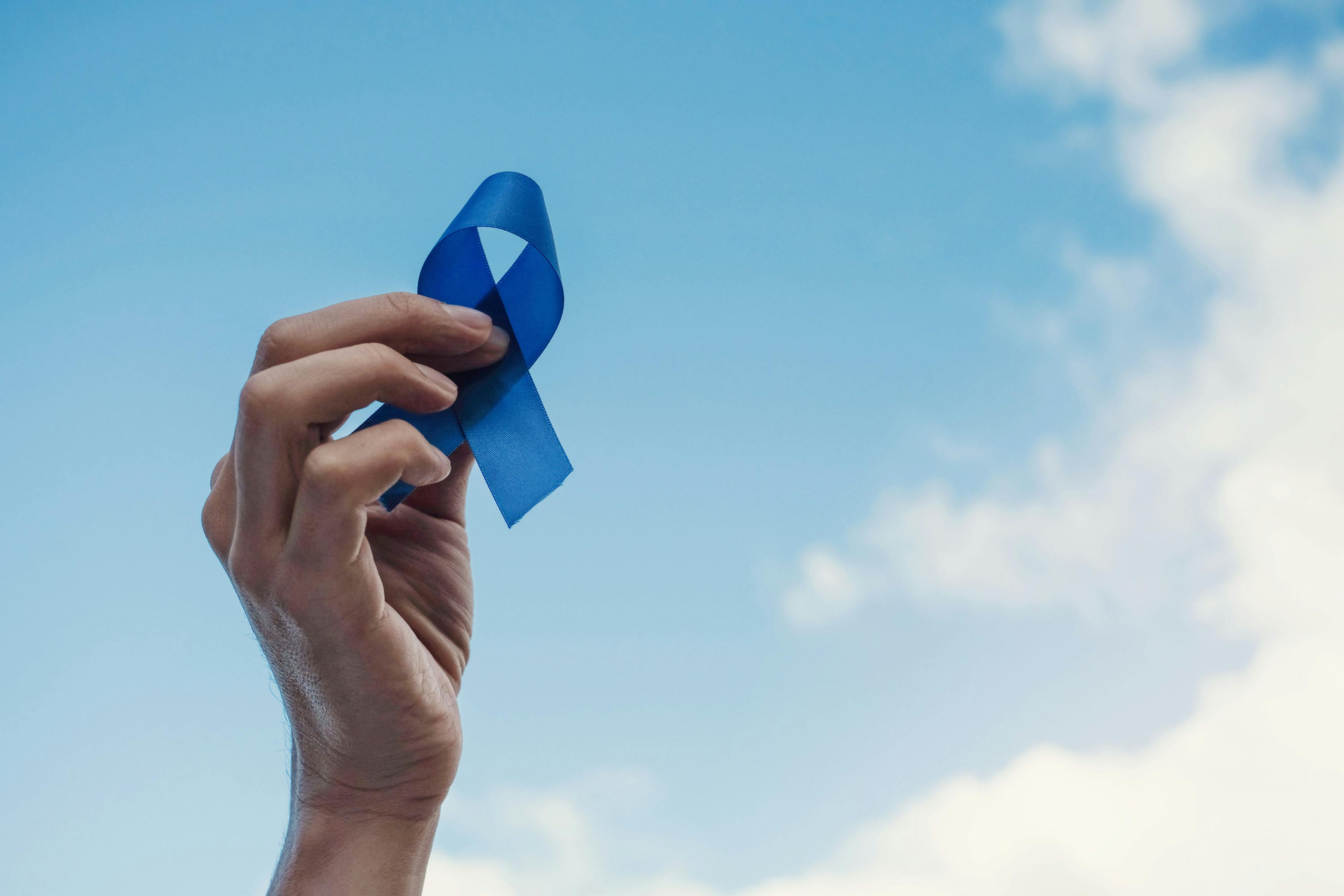 Man Hands holding blue ribbon over blue sky, Prostate Cancer Awareness, November blue, Movember Men health awareness - Image credit: SewcreamStudio | stock.adobe.com 