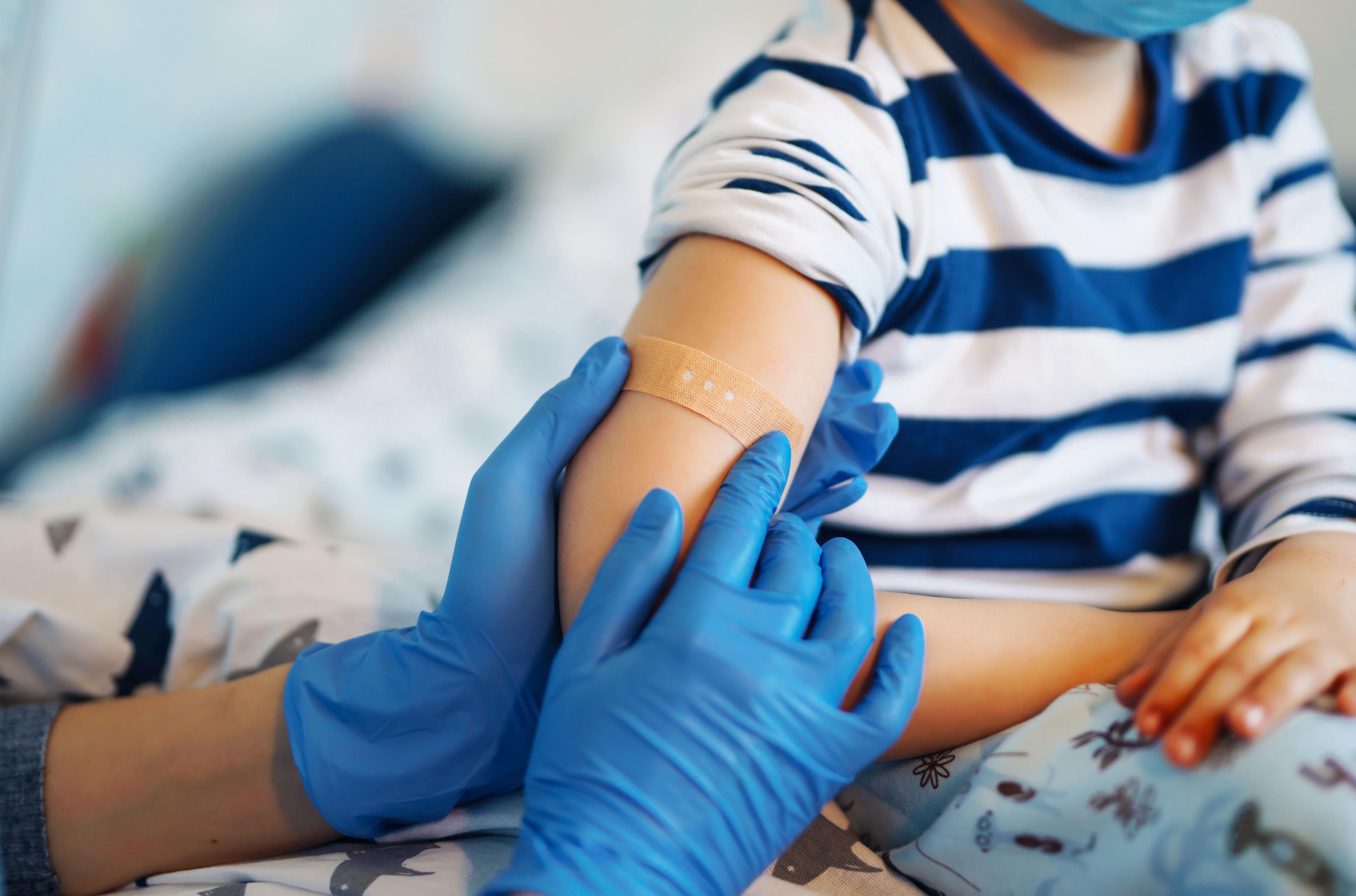 Children's doctor vaccinating little boy at home. 