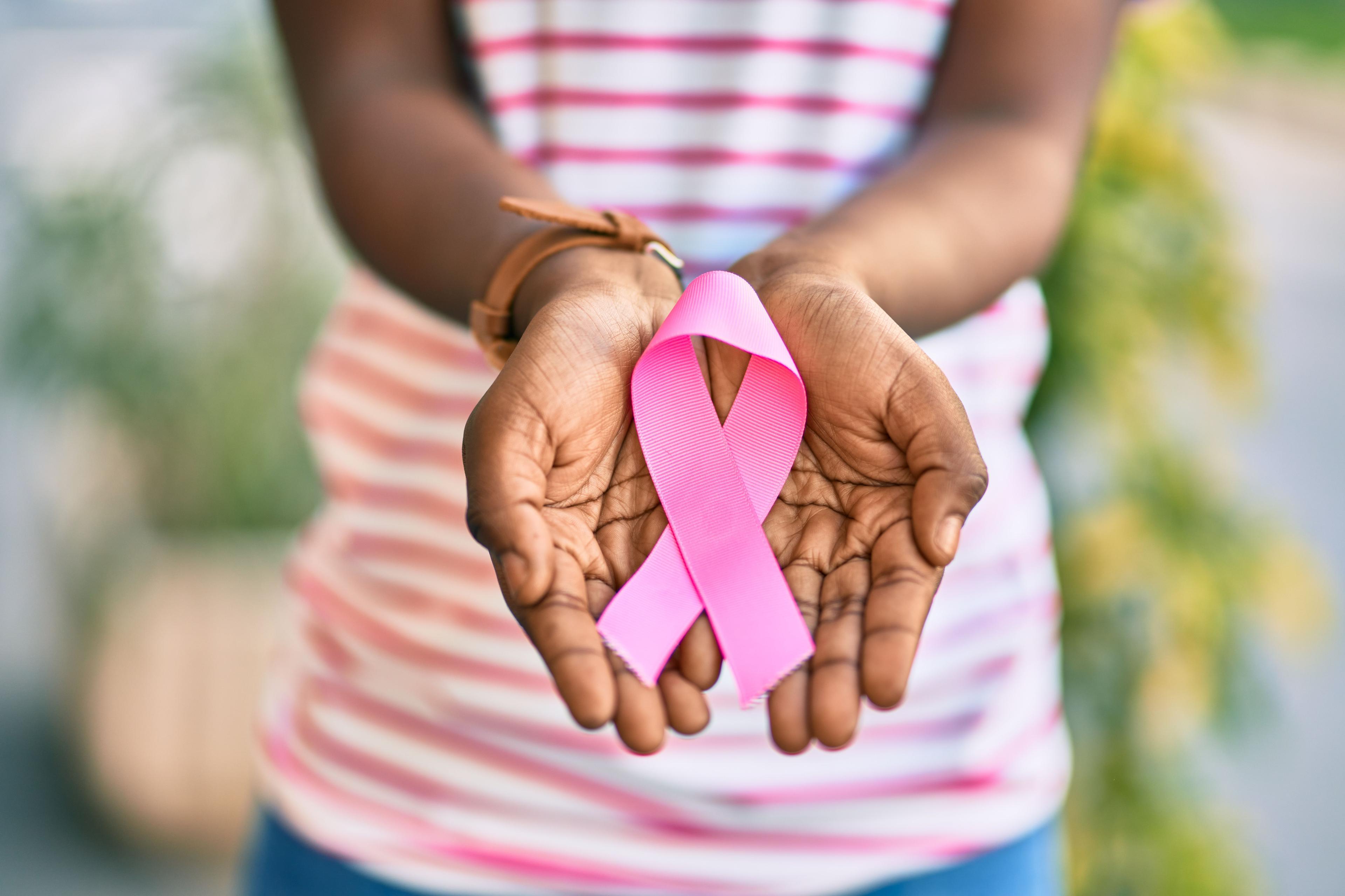 Black woman holding pink ribbon, breast cancer awareness -- Image credit: Krakenimages.com | stock.adobe.com