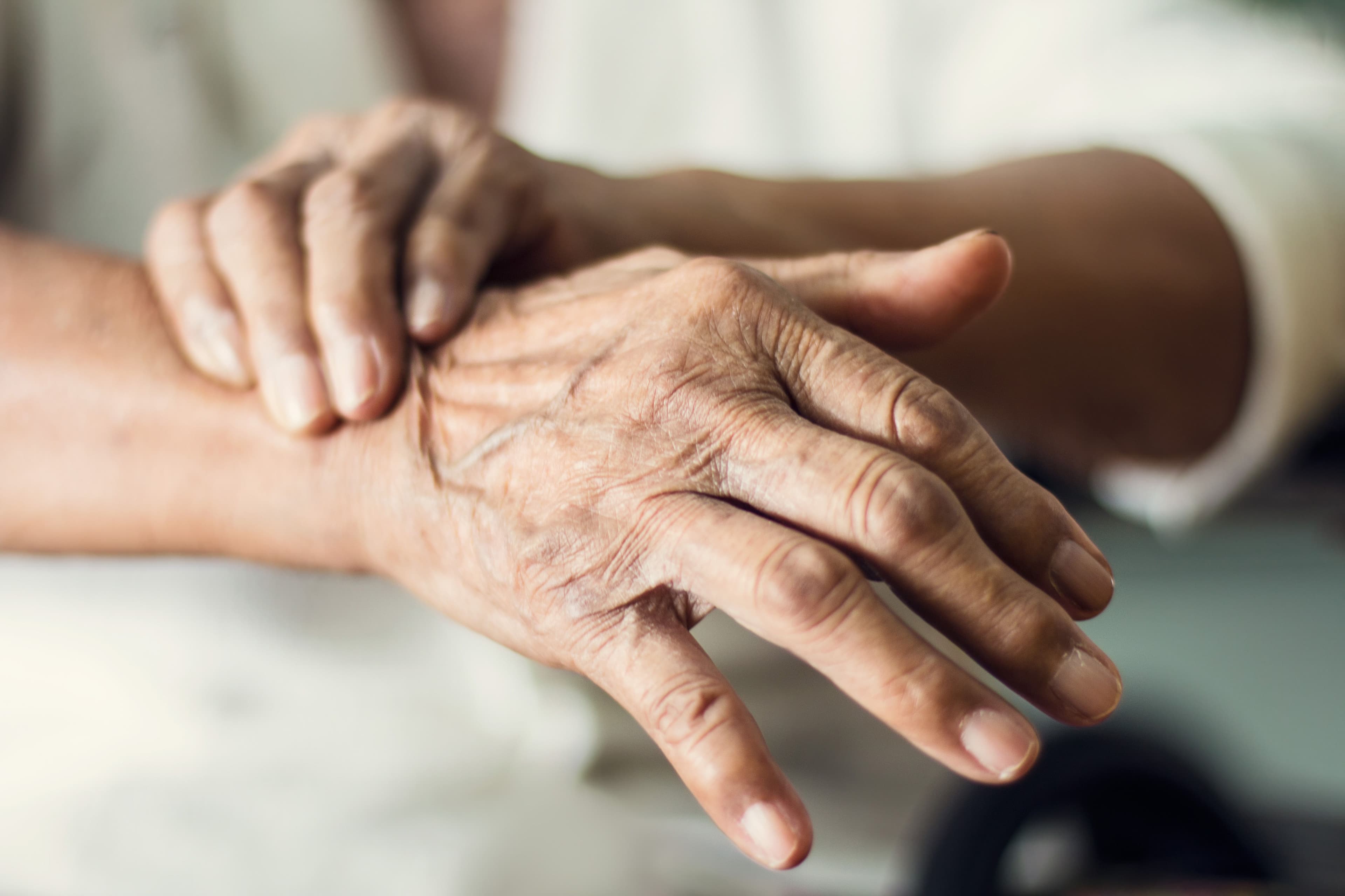 Close up hands of senior elderly woman patient suffering from parkinson's disease symptoms