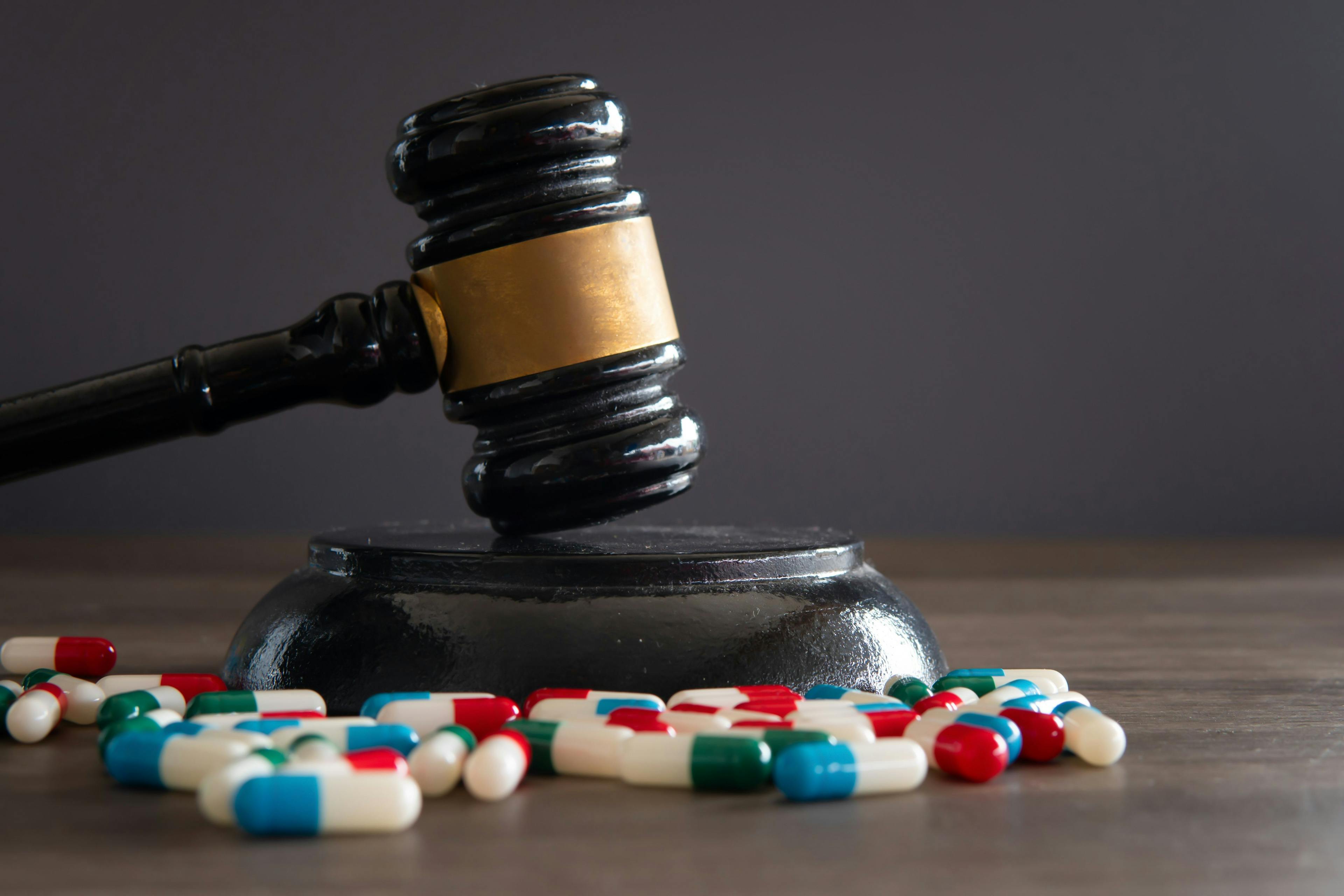 Closeup image of colorful medicine pills and judge gavel on table. Medical law concept - Image credit: izzuan | stock.adobe.com