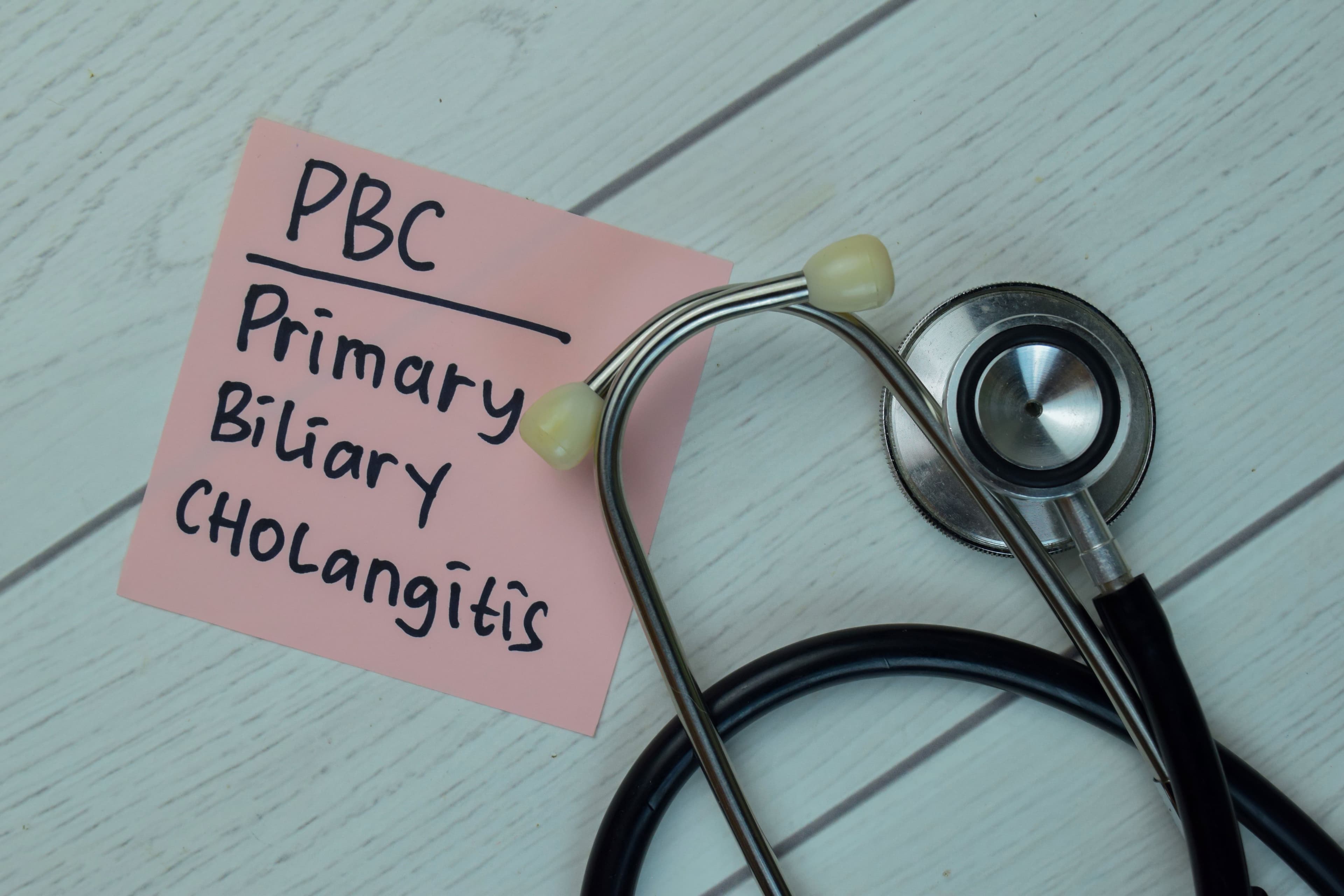 PBC - Primary Biliary Cholangitis write on sticky notes isolated on Wooden Table