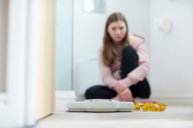 Unhappy Teenage Girl Sitting In Bathroom Looking At Scales And Tape Measure - Image credit: Daisy Daisy | stock.adobe.com