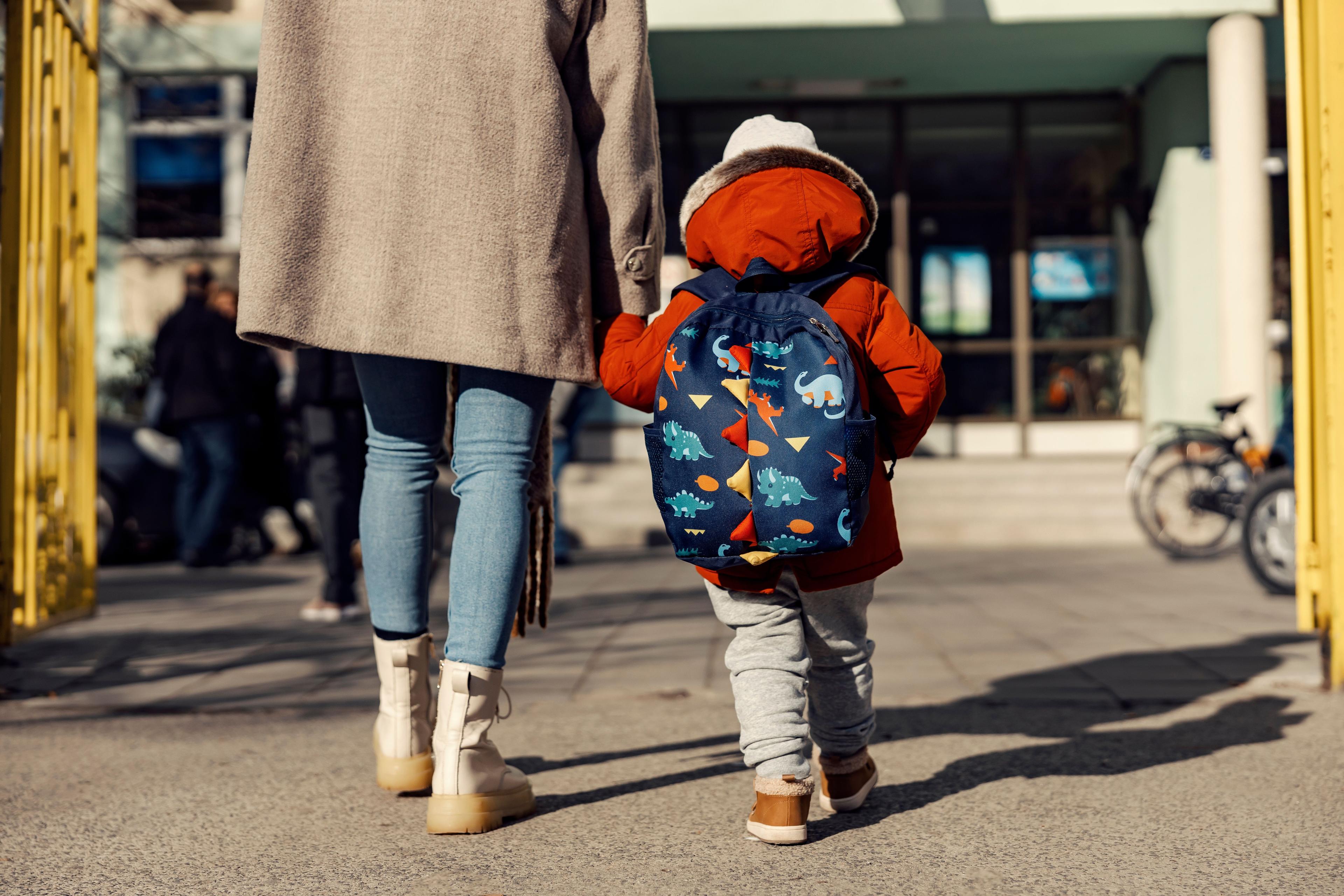 Kindergartener walking into school with their parent.