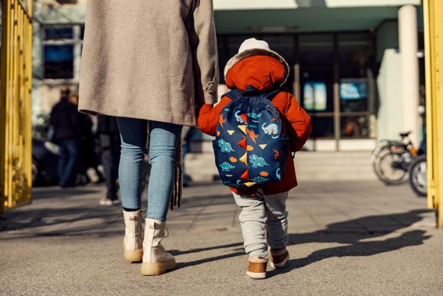 Kindergartener walking into school with parent.