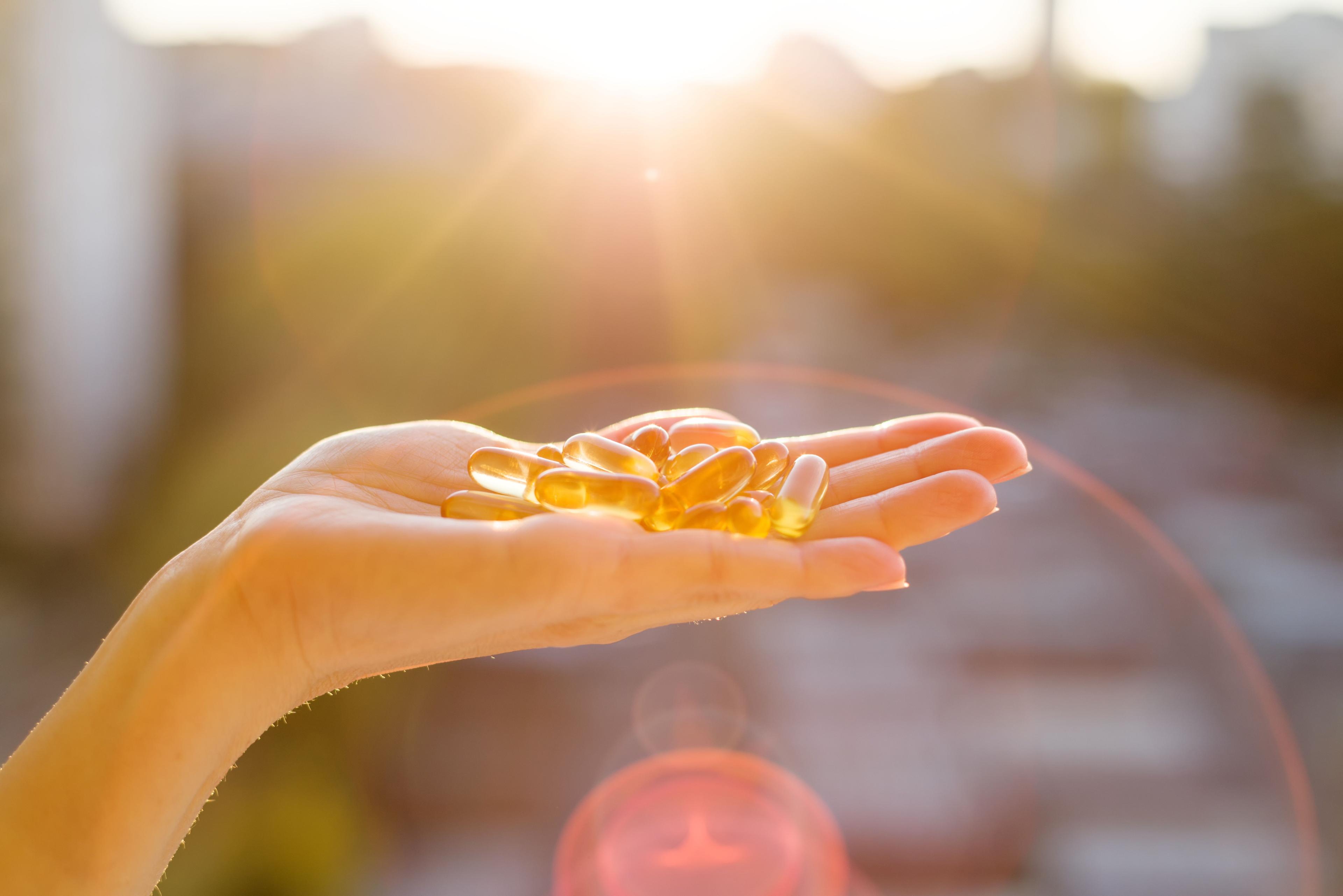 Hand of a woman holding fish oil Omega-3 capsules, urban sunset background. Healthy eating, medicine, health care, food supplements and people concept- Image credit: Valerii Honcharuk | stock.adobe.com