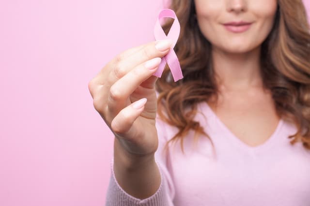 Woman holding pink ribbon for breast cancer awareness -- Image credit: marina_li_1 | stock.adobe.com 