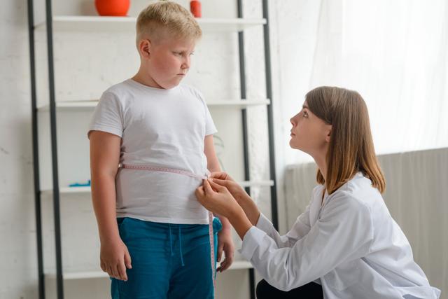 Little chubby boy being measured by a friendly doctor.