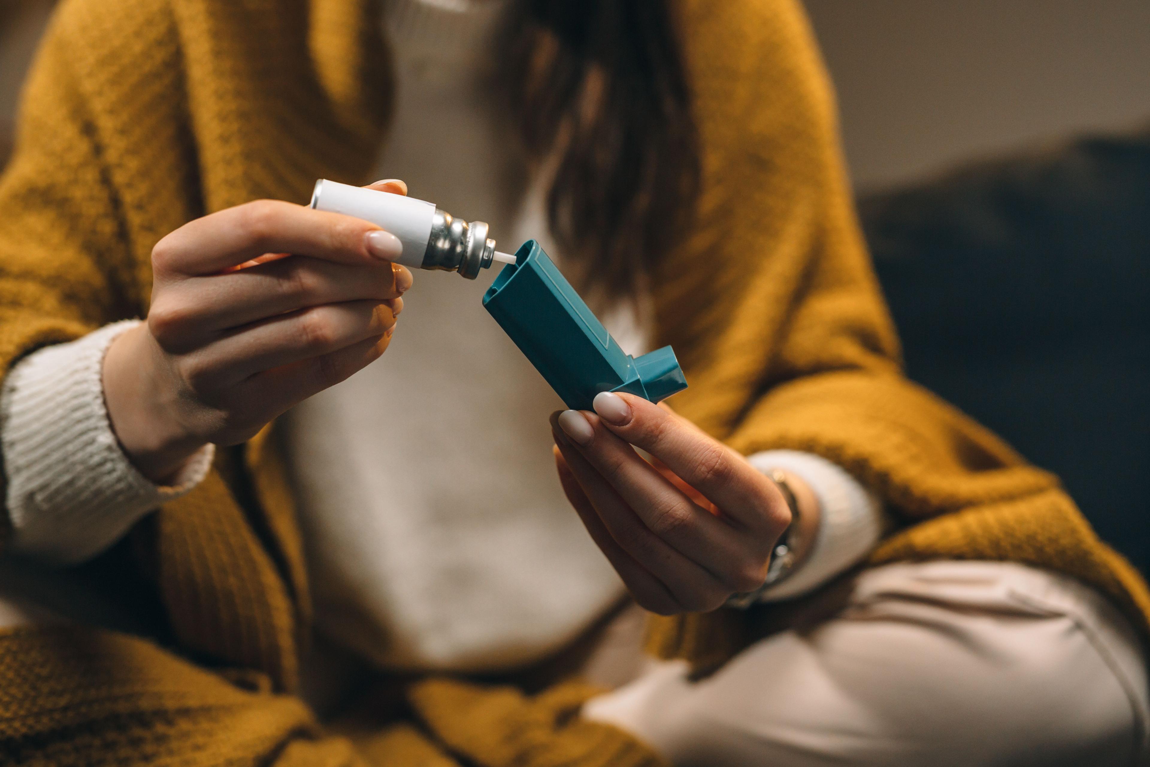 Woman holding asthma inhaler -- Image credit: cherryandbees | stock.adobe.com