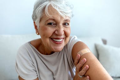 Proud mature woman smile after vaccination with bandage on arm. Beautiful smiling senior woman 70s after receiving the coronavirus vaccine. Elderly lady getting immunization via anti-viral vaccine - Image credit: Jelena Stanojkovic | stock.adobe.com 