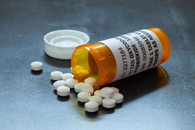 Prescription bottle with backlit oxycodone tablets.