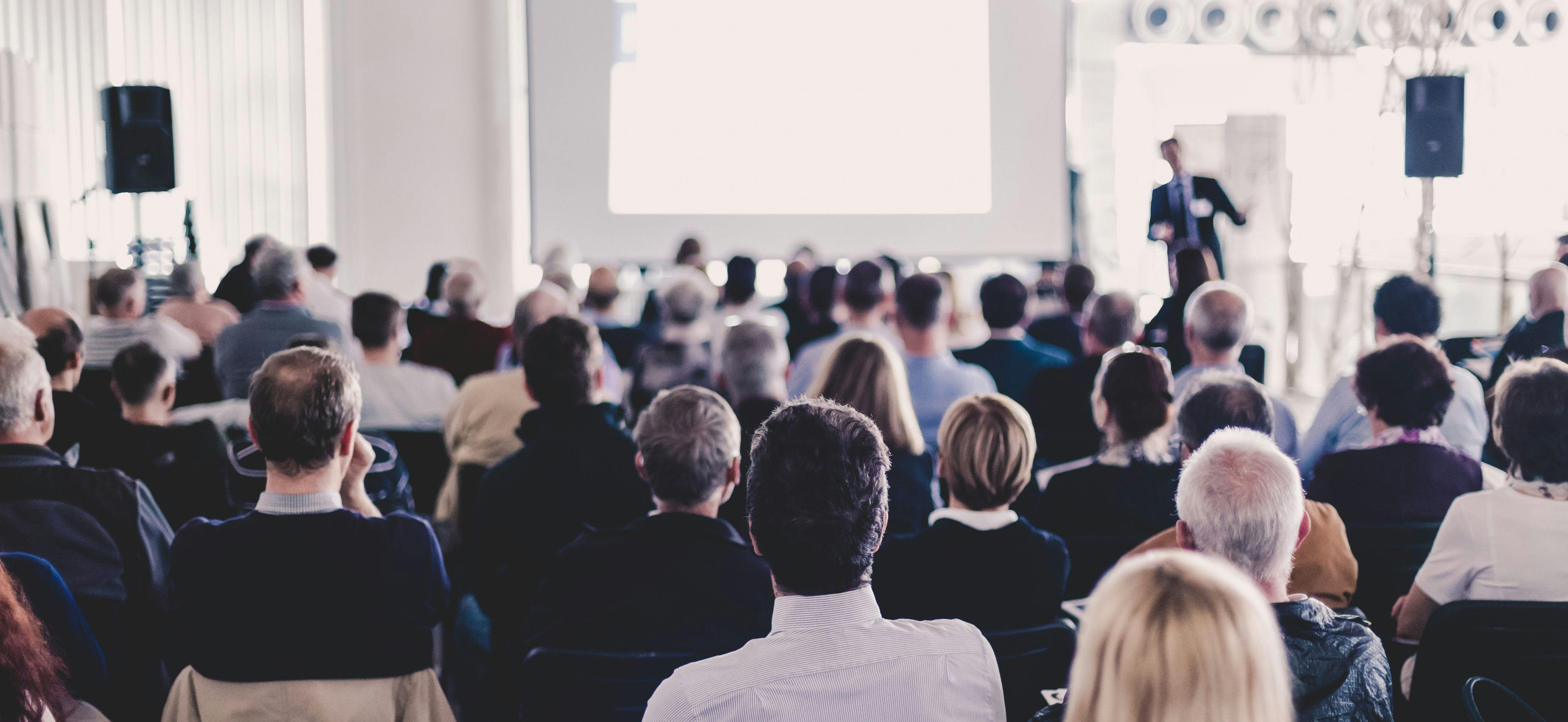 Speaker Giving a Talk at Business Meeting. Audience in the conference hall. Business and Entrepreneurship. Panoramic composition suitable for banners - Image credit: kasto | stock.adobe.com 