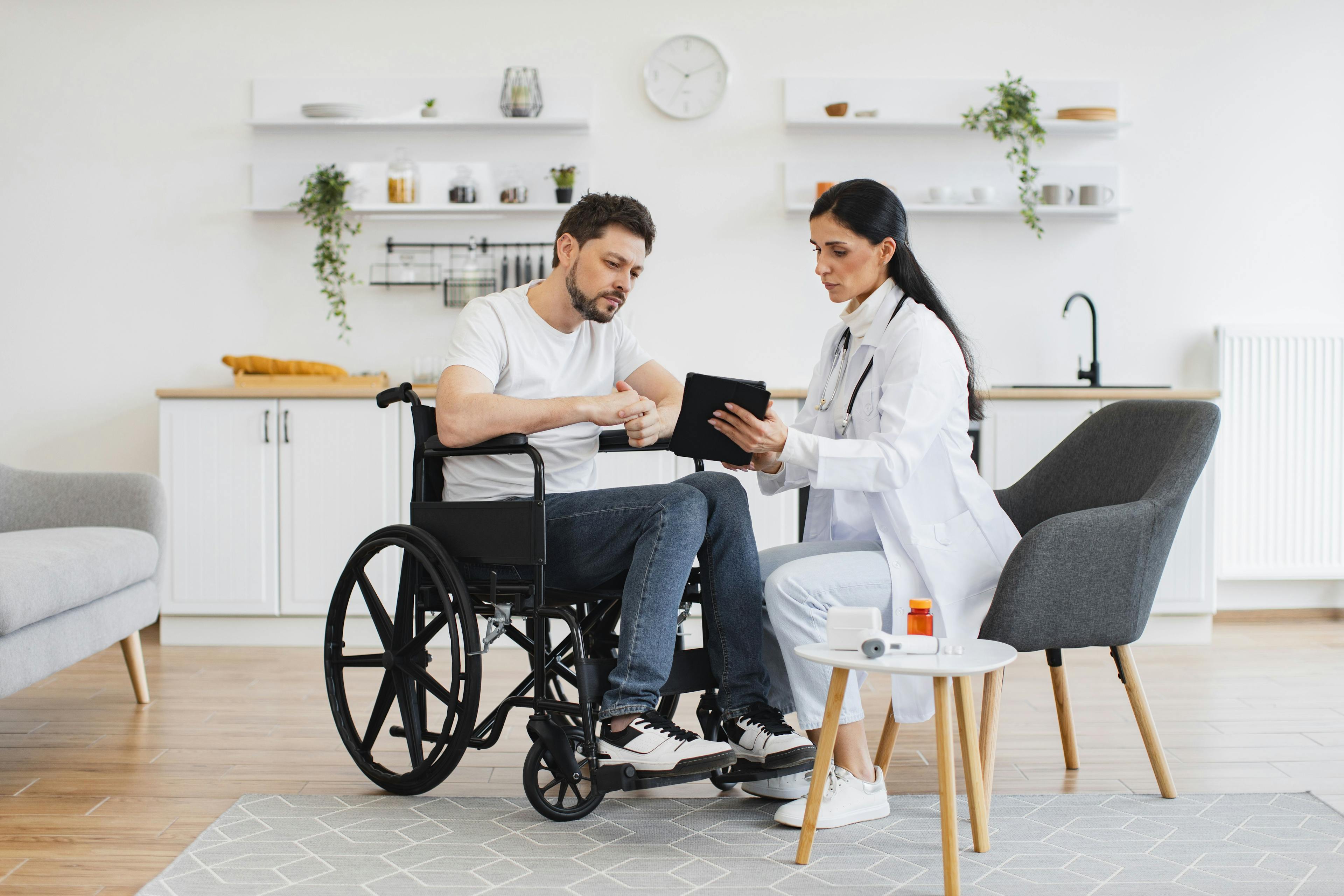 Doctor talking with a patient in a wheelchair about multiple sclerosis diagnosis, medication, therapy 